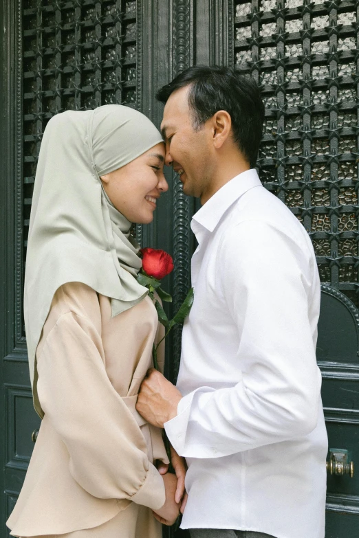 a man and a woman standing next to each other, pexels contest winner, hurufiyya, holding a rose, white hijab, square, asian