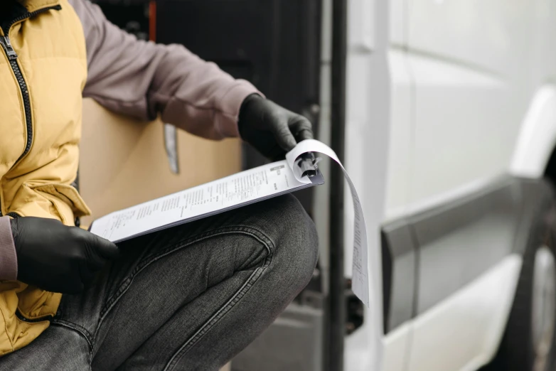 a person sitting on the side of a van reading a book, private press, inspect in inventory image, packaging, a close up shot, thumbnail