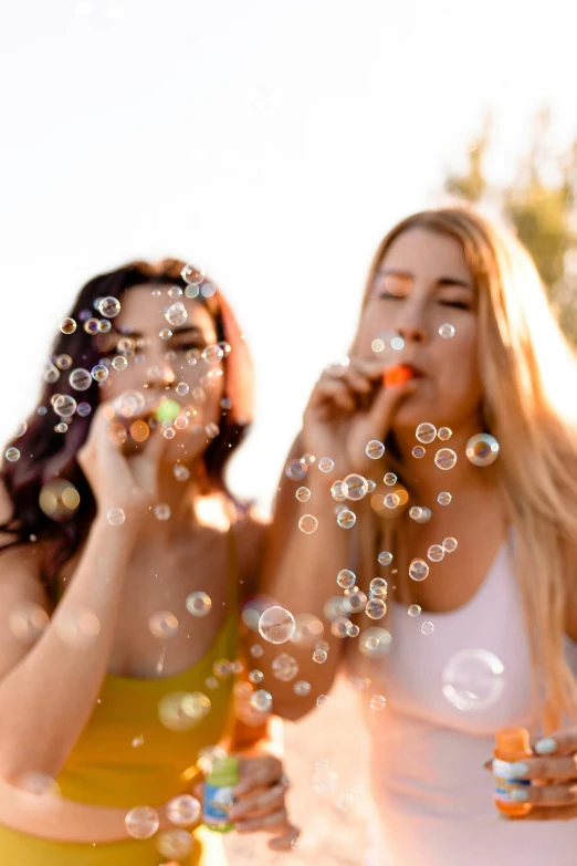 a couple of women standing next to each other blowing bubbles, a picture, trending on pexels, happening, bubbling skin, soda, group photo, one blonde and one brunette