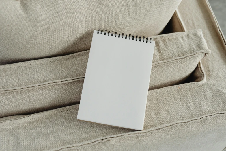 a notepad sitting in the pocket of a couch, an album cover, inspired by Agnes Martin, unsplash, white, whiteboards, beige