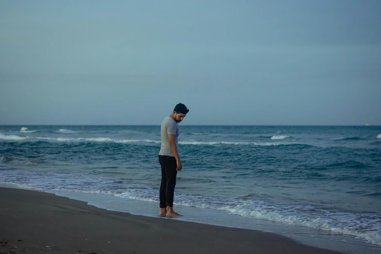 a man standing on top of a beach next to the ocean, she's sad, a portrait of rahul kohli, full body picture, [ cinematic