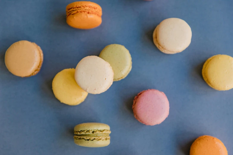 a bunch of macarons sitting on top of a blue surface, trending on pexels, thumbnail, background image, multi - coloured, male and female