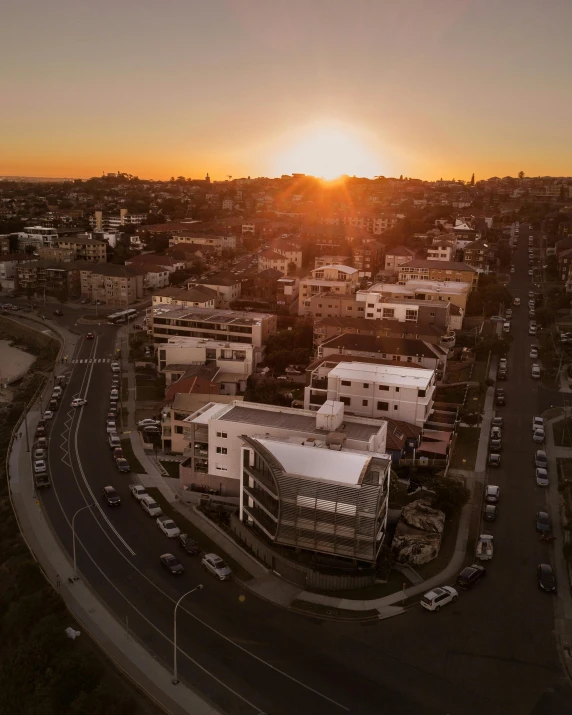an aerial view of a city at sunset, by Lee Loughridge, pexels contest winner, bondi beach in the background, view from the streets, white buildings, apartment