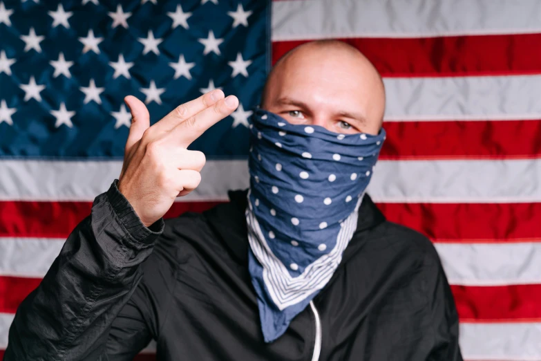 a bald man wearing a bandana in front of an american flag, inspired by Brian 'Chippy' Dugan, unsplash, graffiti, middle finger, winter soldier mask, instagram picture, menacing pose