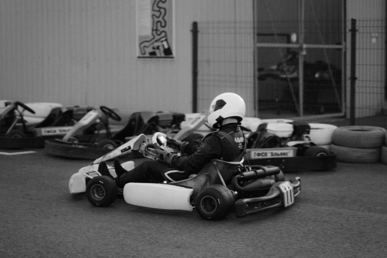 a black and white photo of a man driving a go kart, samma van klaarbergen, beginner, uploaded, facing sideways