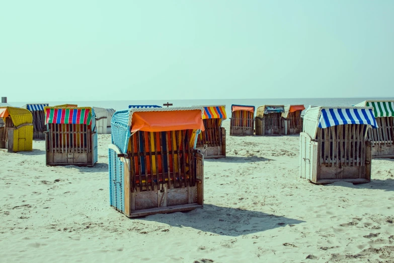 a row of beach chairs sitting on top of a sandy beach, a colorized photo, unsplash contest winner, german romanticism, colorful caparisons, profile image, dunkirk, medium format