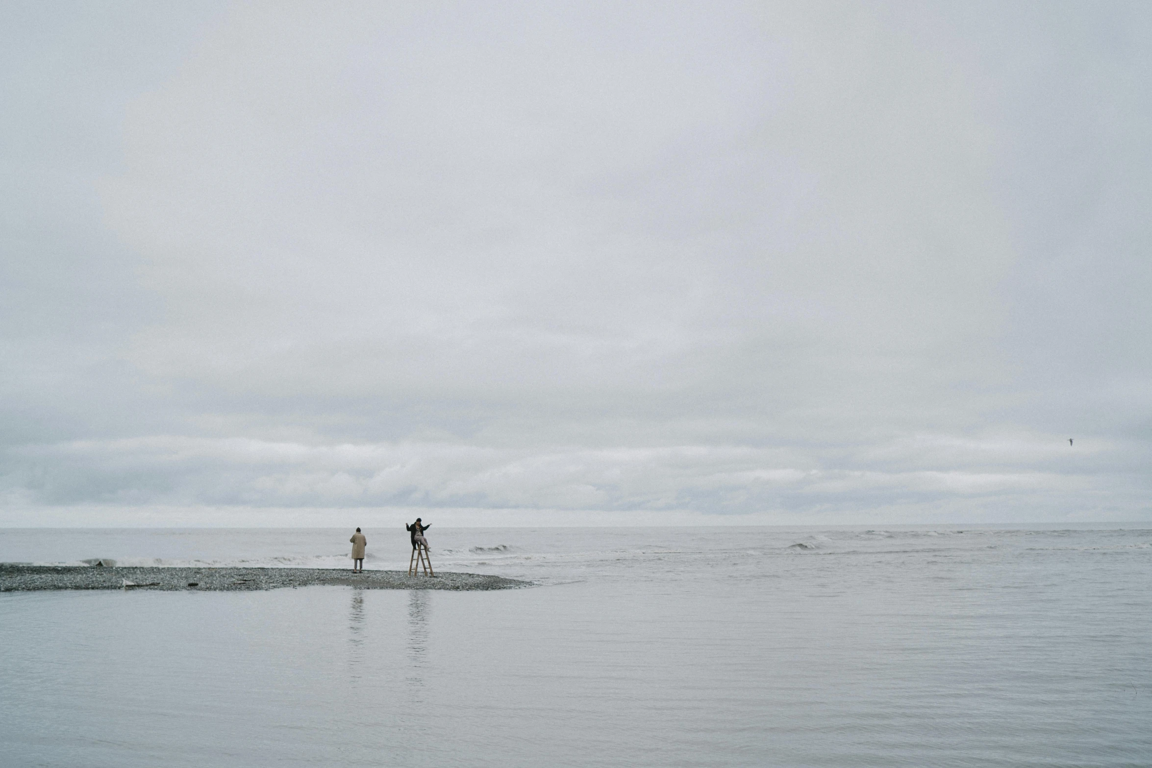 a couple of people that are standing in the water, unsplash, minimalism, overcast gray skies, haida, ignant, hunting