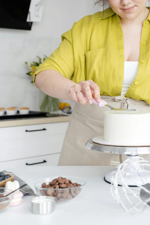 a woman decorating a cake in a kitchen, trending on pexels, stainless steal, white, promo image, tall