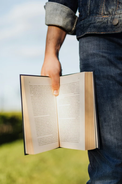 a man holding an open book in his hand, in the sun, lit up, fully functional, readability