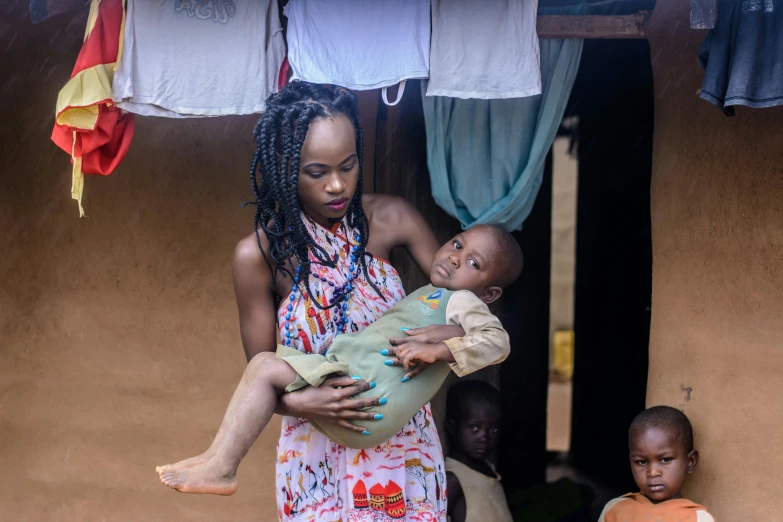 a woman holding a child in her arms, by Ingrida Kadaka, pexels contest winner, loin cloth, hanging, thumbnail, getty images proshot