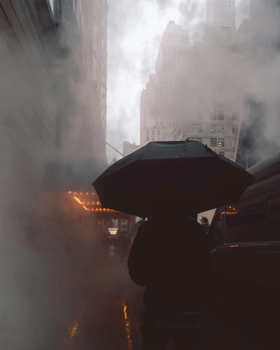 a person walking in the rain with an umbrella, buildings and smoke, snapchat photo, heavy winter aesthetics, instagram post