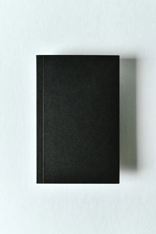 a black book sitting on top of a white table, front, ignant, full product shot, black textured