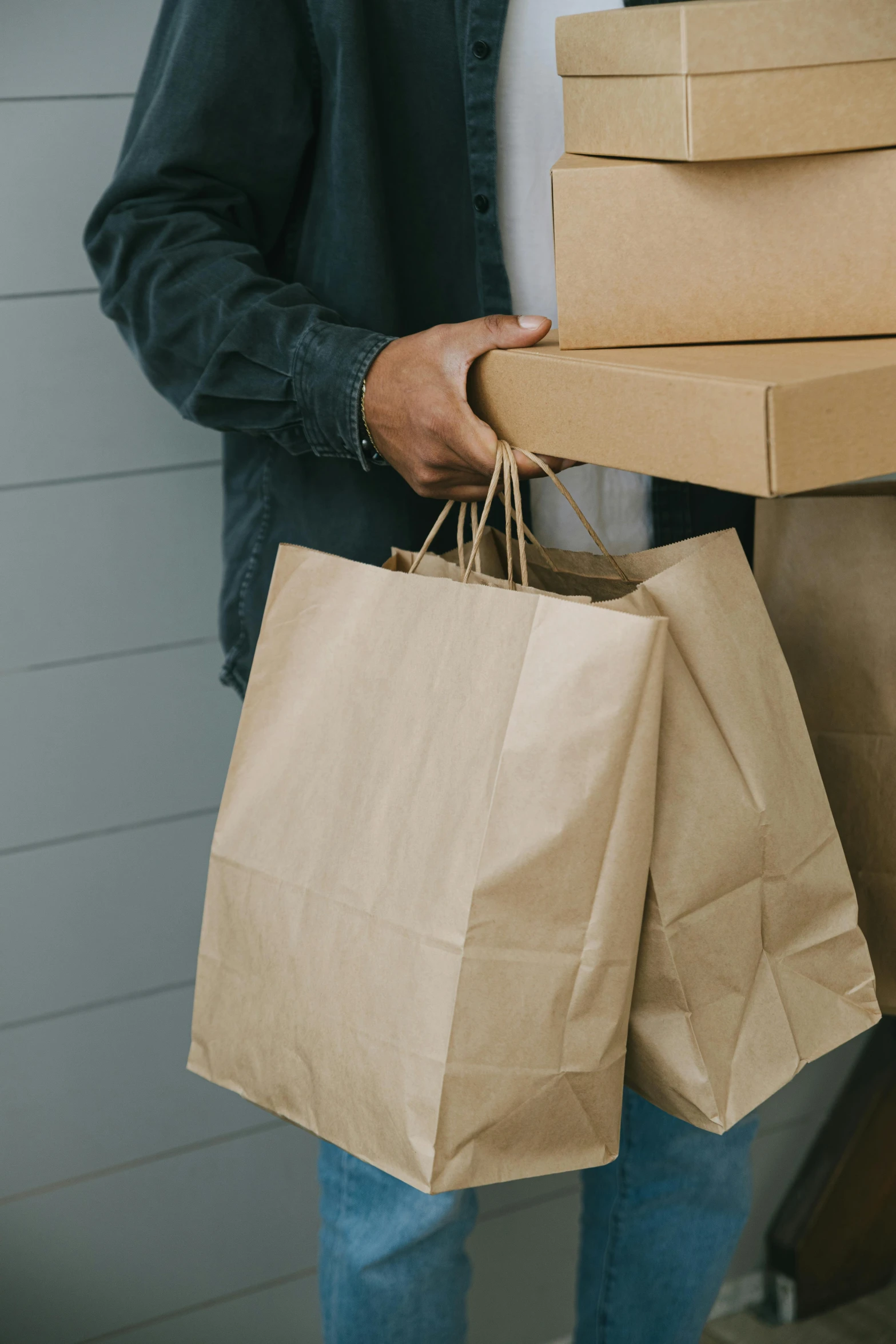 a man holding a stack of boxes in his hands, by Everett Warner, trending on pexels, renaissance, wearing a baggy, shopping groceries, brown paper, gold