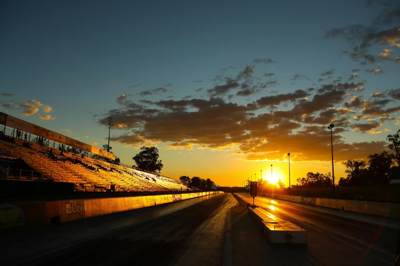 the sun is setting behind the bleachers in the bleachers, by Tom Bonson, pexels contest winner, happening, motorsports photography, roth's drag nut fuel, caulfield, profile image