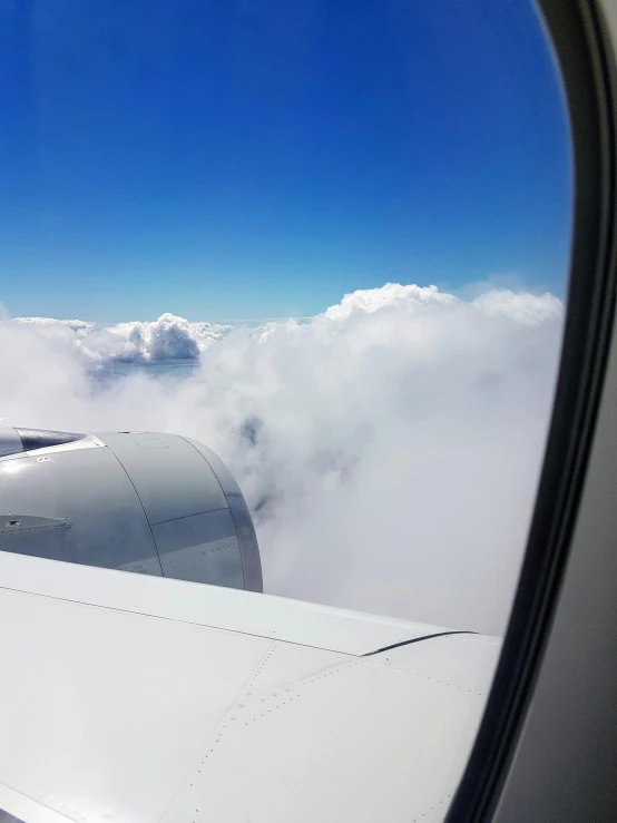 a view of the wing of an airplane through a window, floating lands in-clouds, looking towards the camera, swirly clouds, helmet view