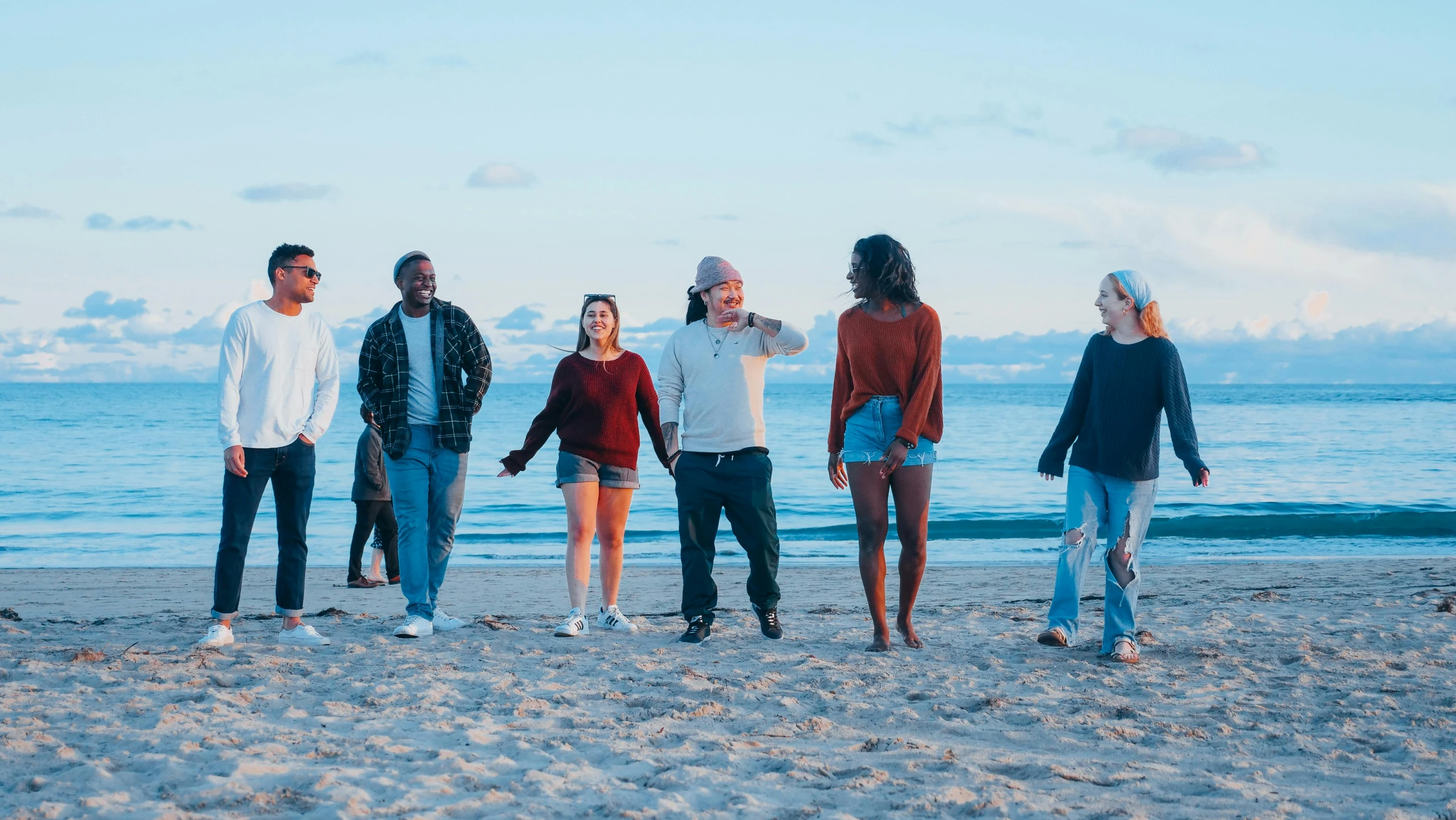 a group of people standing on top of a sandy beach, profile image