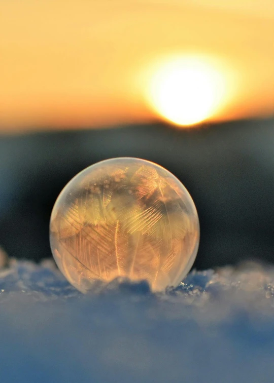 a snow globe sitting on top of a snow covered ground, during a sunset