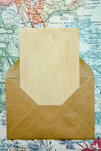a brown envelope sitting on top of a map, tropical wood, unframed, wood materials, greeting card