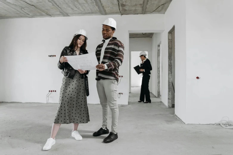 a couple of people that are standing in a room, pexels contest winner, arbeitsrat für kunst, building plans, dressed in expensive clothes, white concrete floor, developers