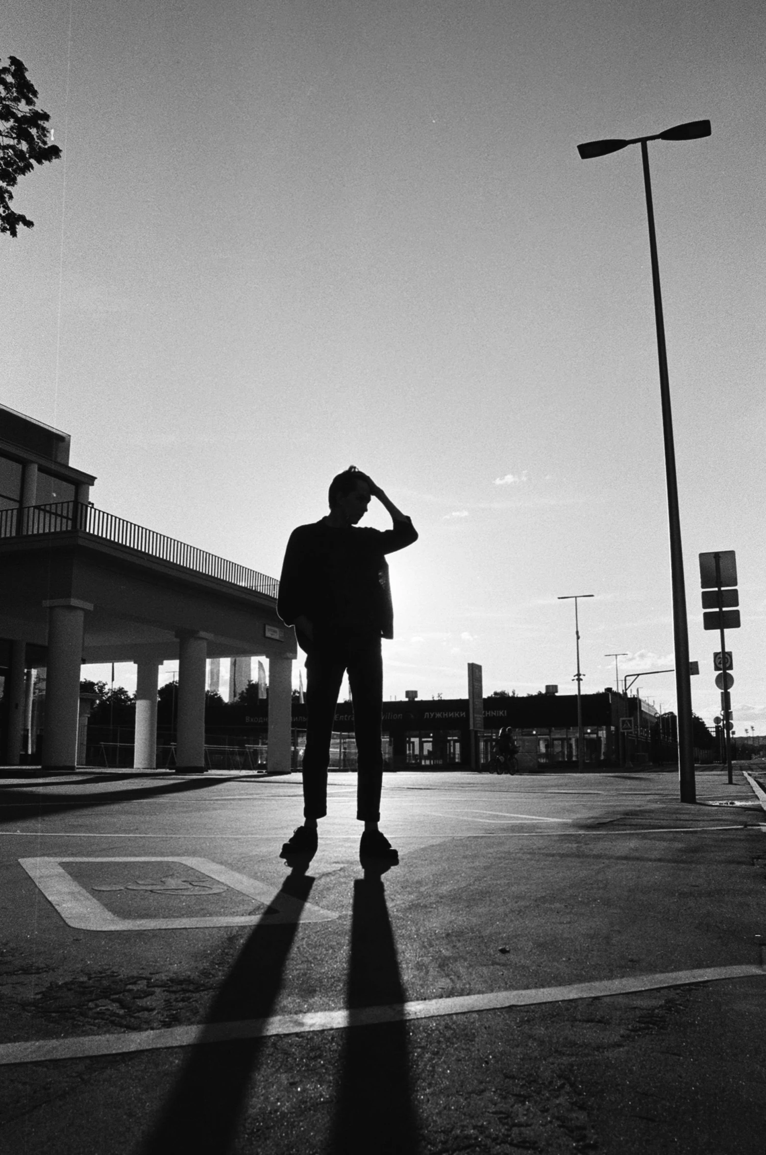 a person standing in the middle of a street, a black and white photo, ((sunset)), alternate album cover, outside in parking lot, profile image