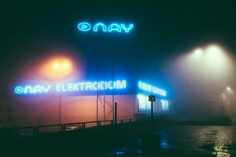 a neon sign on the side of a building, by Adam Marczyński, unsplash contest winner, retrofuturism, foggy weather, blue neon, ektachrome color photograph, in low fog