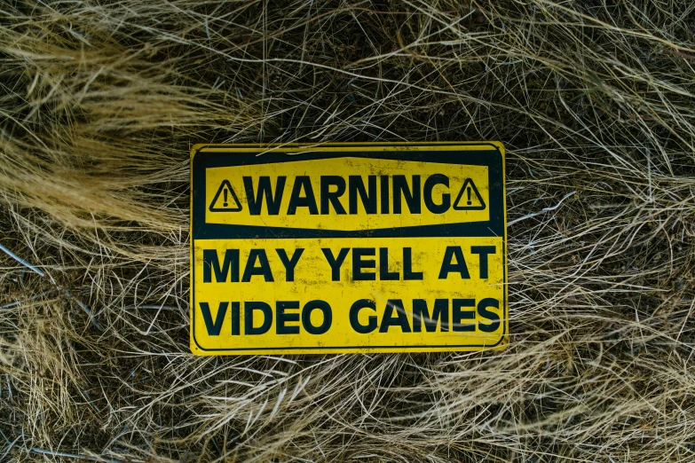 a yellow warning sign sitting on top of a pile of hay, pexels, graffiti, playing video games, avatar image, vhs, hey