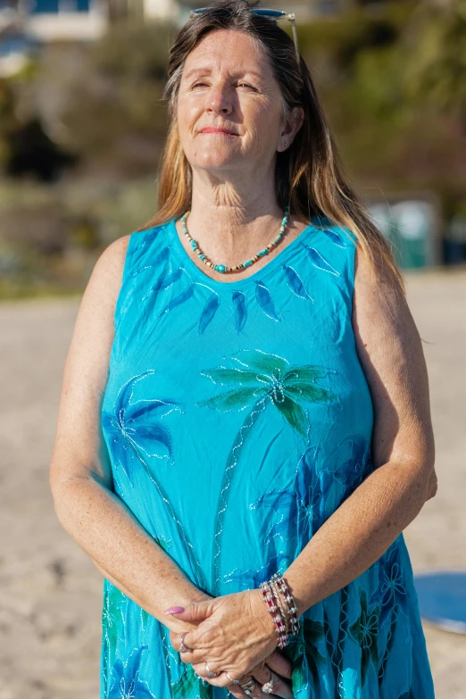 a woman standing on top of a sandy beach, a portrait, by Lynn Pauley, sleeveless tops, palm pattern visible, turquoise, medium close shot