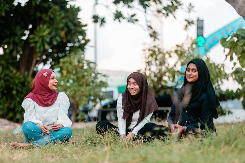 a group of women sitting on top of a grass covered field, inspired by JoWOnder, hurufiyya, in a city park, malaysian, profile image, in a square