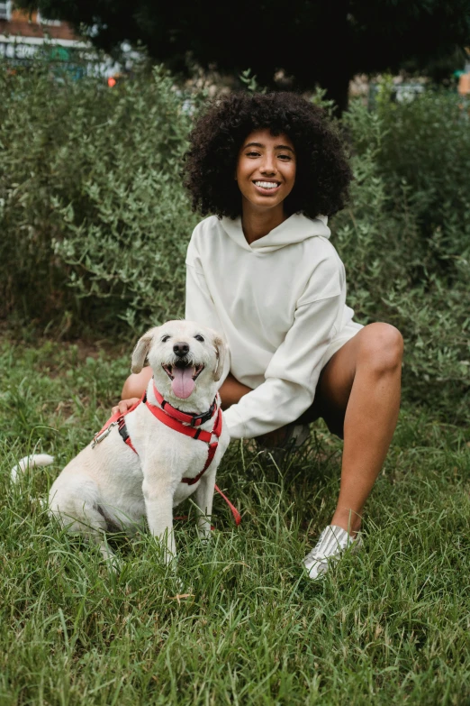 a woman sitting in the grass with her dog, wearing a scarlet hoodie, white, ashteroth, ready to model