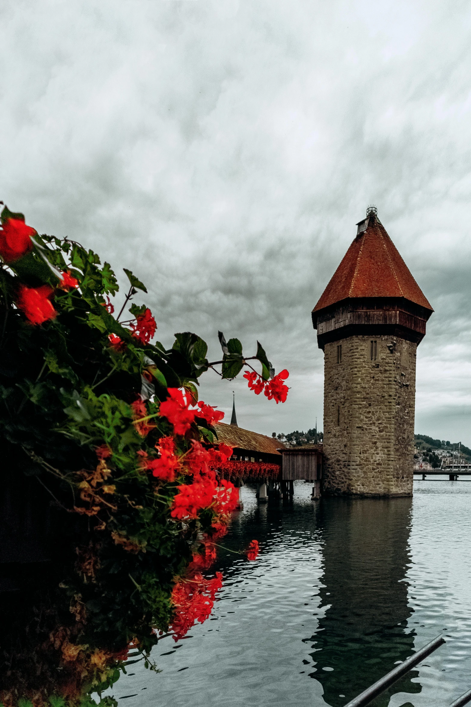 a tower in the middle of a body of water, red flowers, swiss architecture, slide show, cinematic image