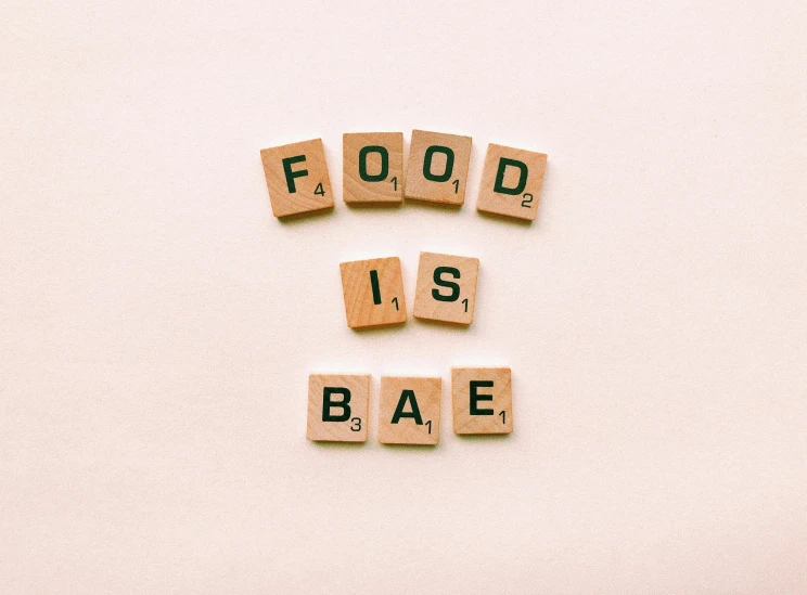 food is bae spelled with scrabbles on a white surface, an album cover, trending on pexels, background image, submissive, beige, vibrant aesthetic