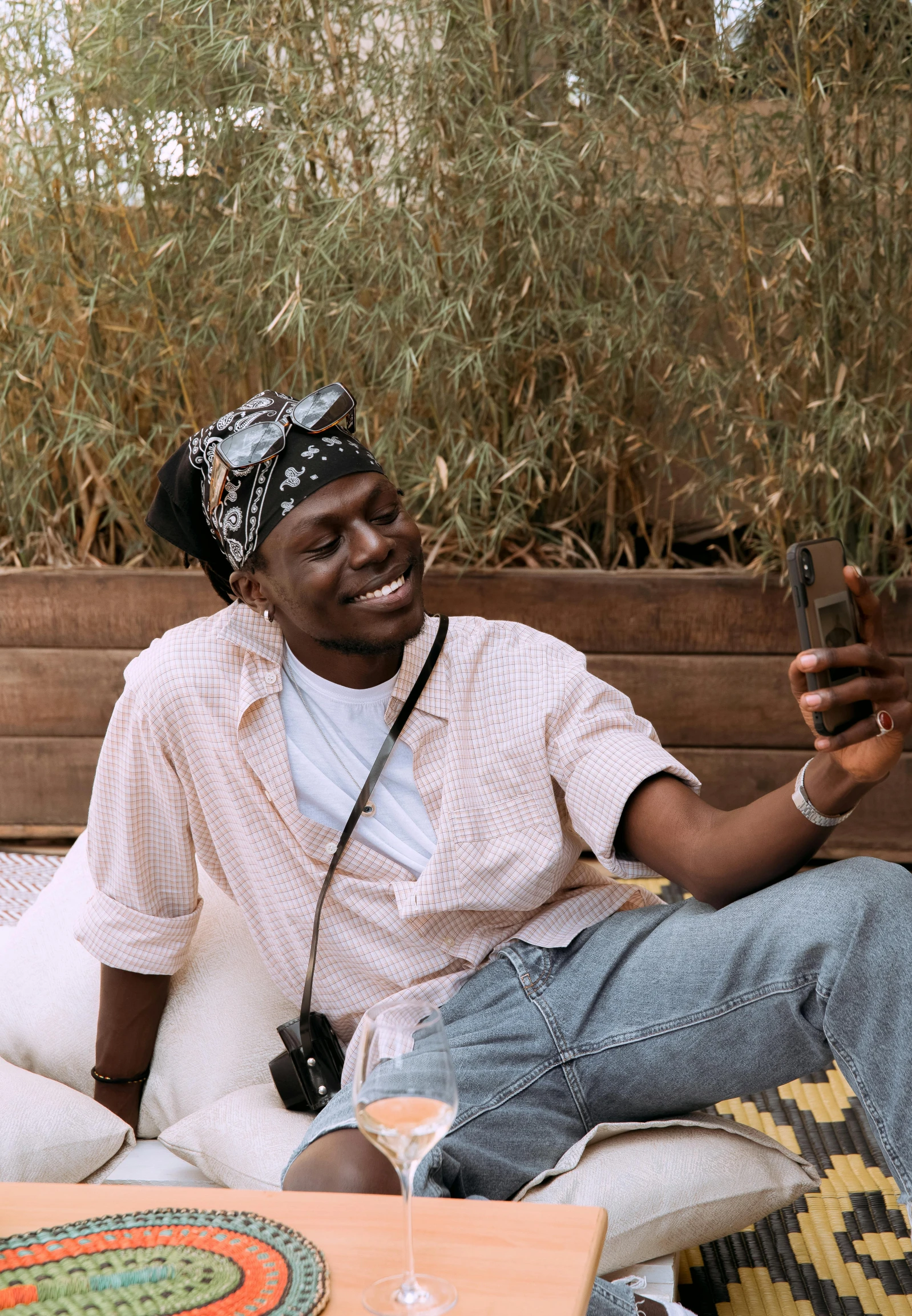 a man sitting on a couch holding a cell phone, trending on unsplash, visual art, brown skin man with a giant grin, in garden, young thug, profile picture