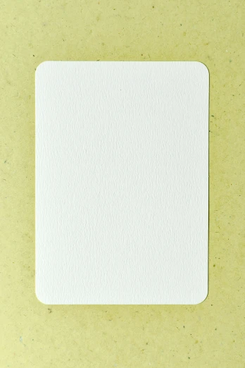 a piece of paper sitting on top of a table, a stipple, rounded corners, whole card, ivory, pure white