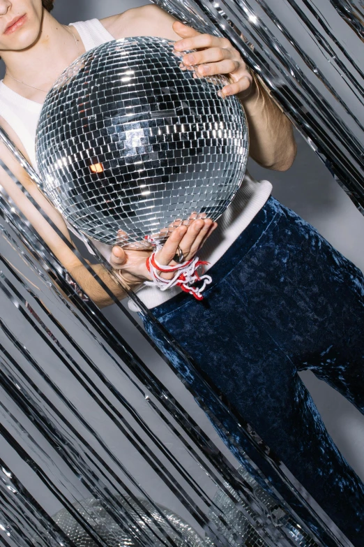 a man standing in front of a mirror holding a disco ball, an album cover, inspired by David LaChapelle, trending on pexels, low detail, dancer, new years eve, circa 1 9 7 9