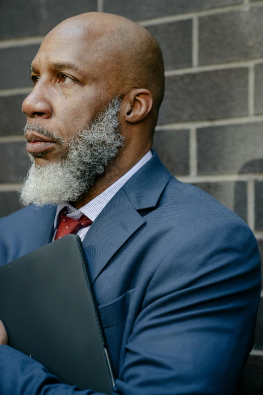 a man in a suit and tie holding a laptop, an album cover, inspired by William H. Mosby, trending on pexels, renaissance, grey beard, looking away, african man, seen from outside