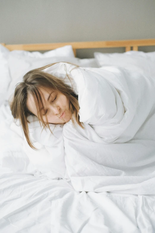 a woman laying on top of a bed covered in white sheets, profile image, wearing robe, covered with blanket, trending photo