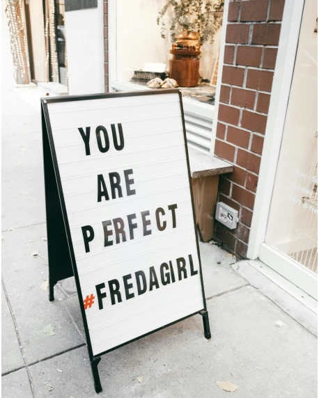a sign sitting on the side of a sidewalk, trending on pexels, feminist art, perfect smile vogue, fireball, shop front, {perfect body}