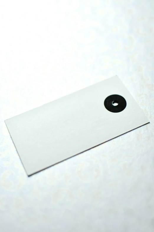 a white business card sitting on top of a table, an album cover, by Shinji Aramaki, private press, black round hole, detail shot, yinyang shaped, tag