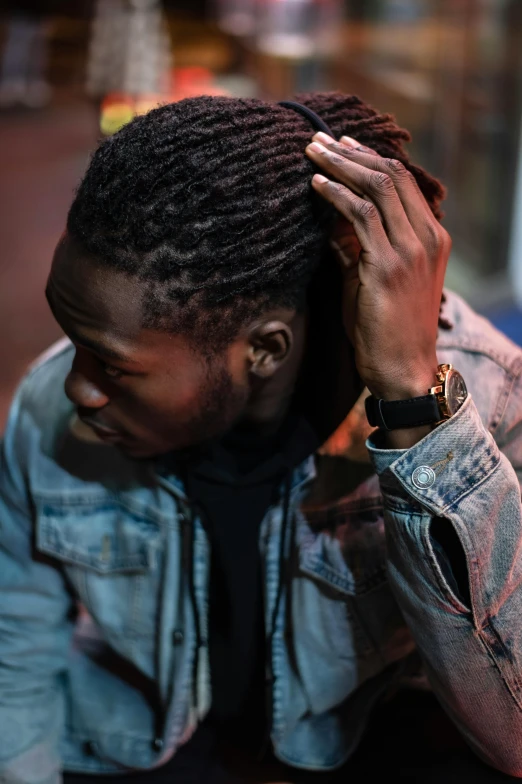 a man sitting on the ground with his head in his hands, trending on pexels, renaissance, dreadlock breed hair, wearing a jeans jackets, looking from shoulder, ( ( dark skin ) )