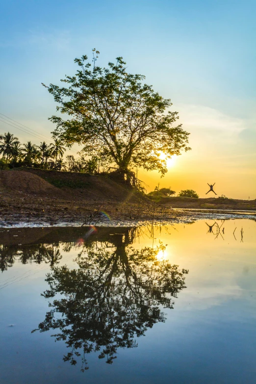 the sun is setting over a body of water, a picture, inspired by Steve McCurry, sumatraism, leaping from babaob tree, ultrawide landscape, myanmar, full frame image