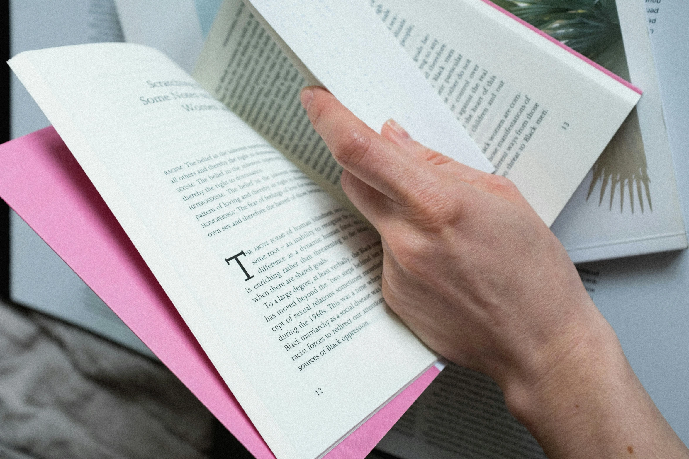 a person is reading a book on a table, a stipple, happening, pink, printed page, highly upvoted, over-shoulder shot