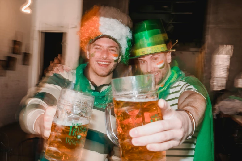 a couple of men standing next to each other holding beer glasses, green hat, fancy dress, highlights, 🚿🗝📝