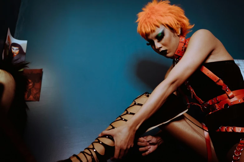 a woman with orange hair sitting on a bed, an album cover, inspired by David LaChapelle, trending on pexels, a 1980s goth nightclub in soho, leg shot, serge lutens, mowhawk