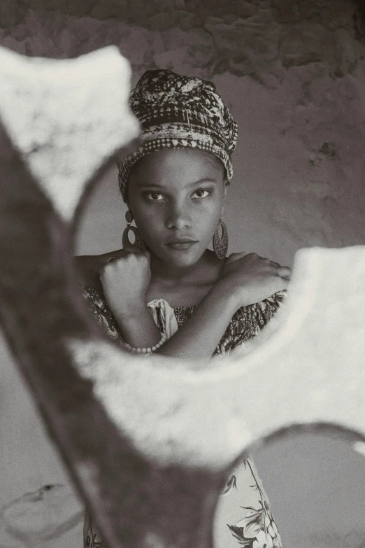 a woman sitting in a chair in front of a mirror, a black and white photo, inspired by Gordon Parks, renaissance, cloth head wrap, promo image, 1980s photograph, girl with a pearl earringl