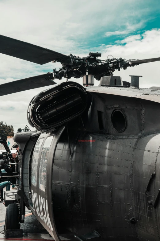 a black helicopter sitting on top of a tarmac, a colorized photo, by Adam Marczyński, pexels contest winner, extreme closeup, military weaponry, with people inside piloting it, [ cinematic