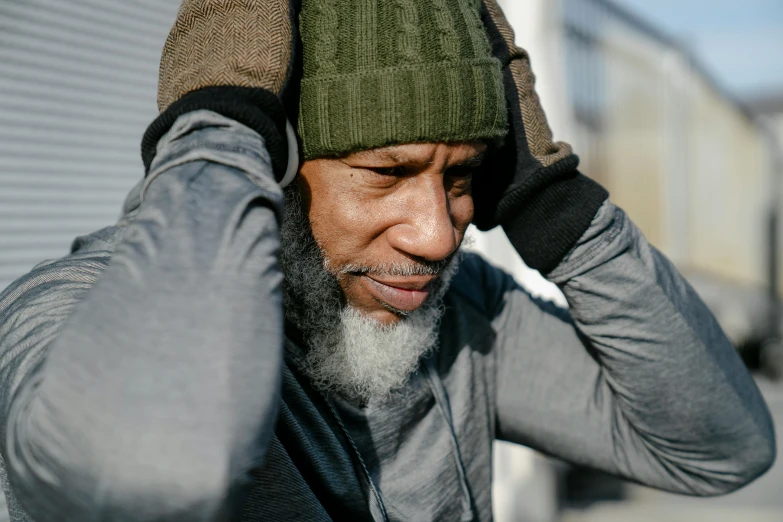 a close up of a person with a hat on, he has a beard and graying hair, wearing fitness gear, stressed out, man is with black skin