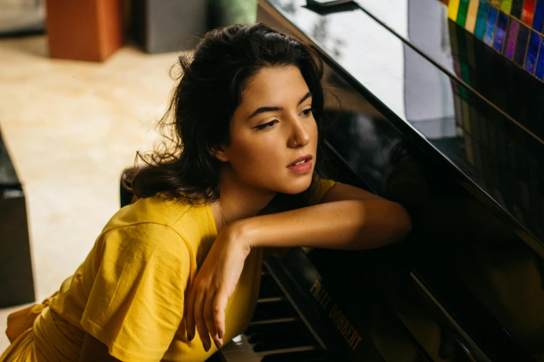 a woman leaning on a piano in a living room, by Julia Pishtar, trending on pexels, wearing yellow croptop, dua lipa, sleepy expression, middle close up composition