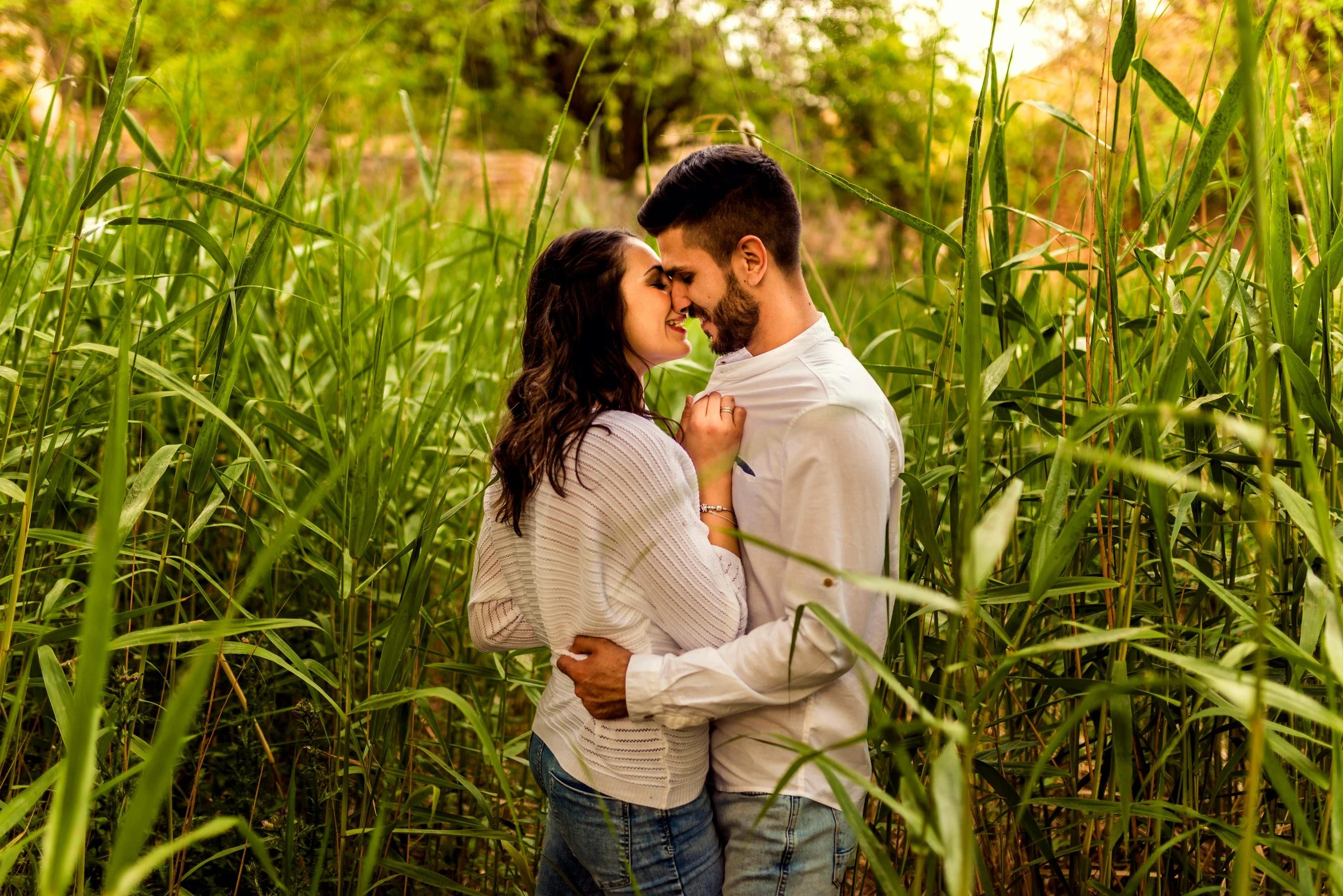 a man and woman standing next to each other in tall grass, a picture, pexels, romanticism, sweet hugs, 15081959 21121991 01012000 4k, background : diego fazio, romantic greenery