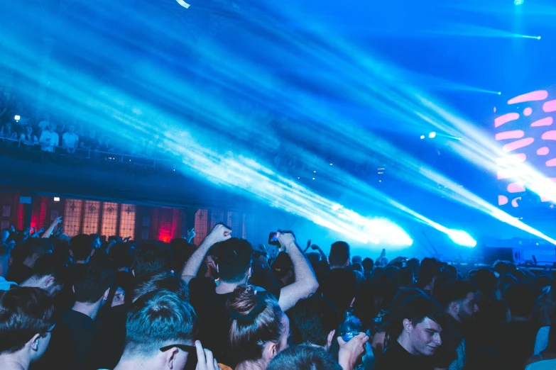 a crowd of people standing in front of a stage, by Nick Fudge, unsplash contest winner, happening, bursting with blue light, “house music rave with dancers, plain background, max prentis