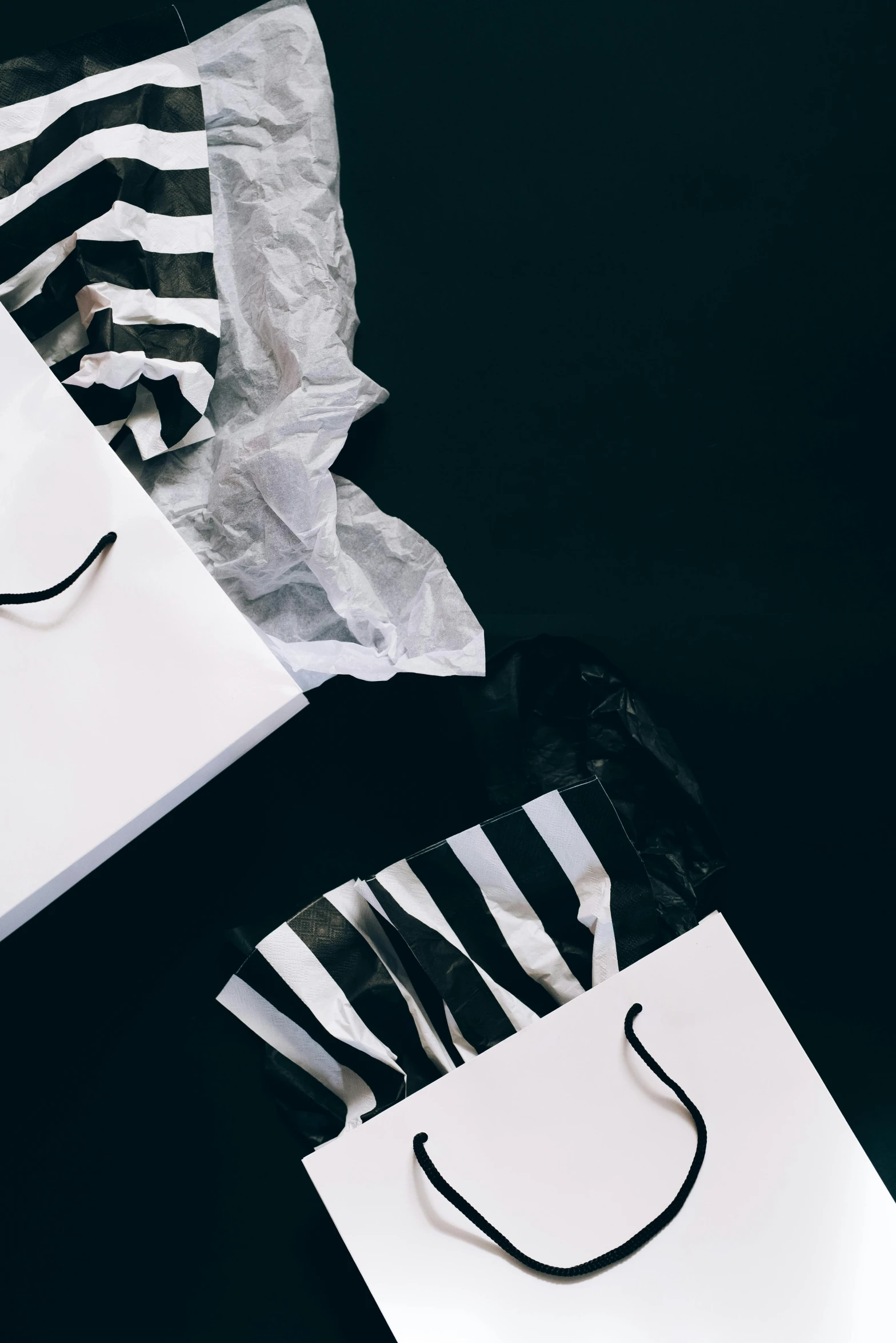 a couple of bags sitting on top of a table, by Julia Pishtar, pexels contest winner, hypermodernism, black stripes, packaging, white ribbon, it's getting dark